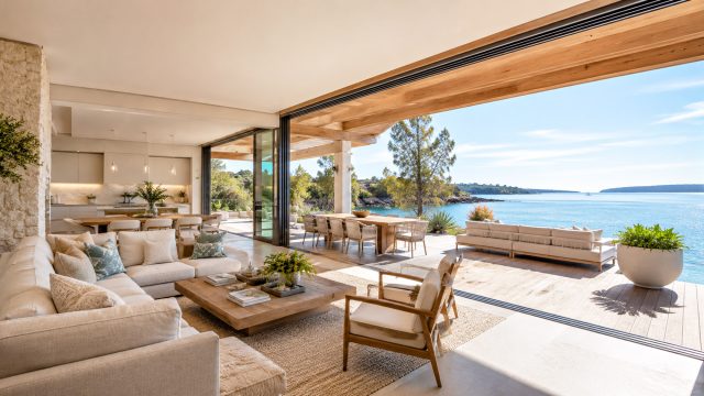 Luxury coastal home with an open-plan living room, expansive terrace, and panoramic waterfront views.