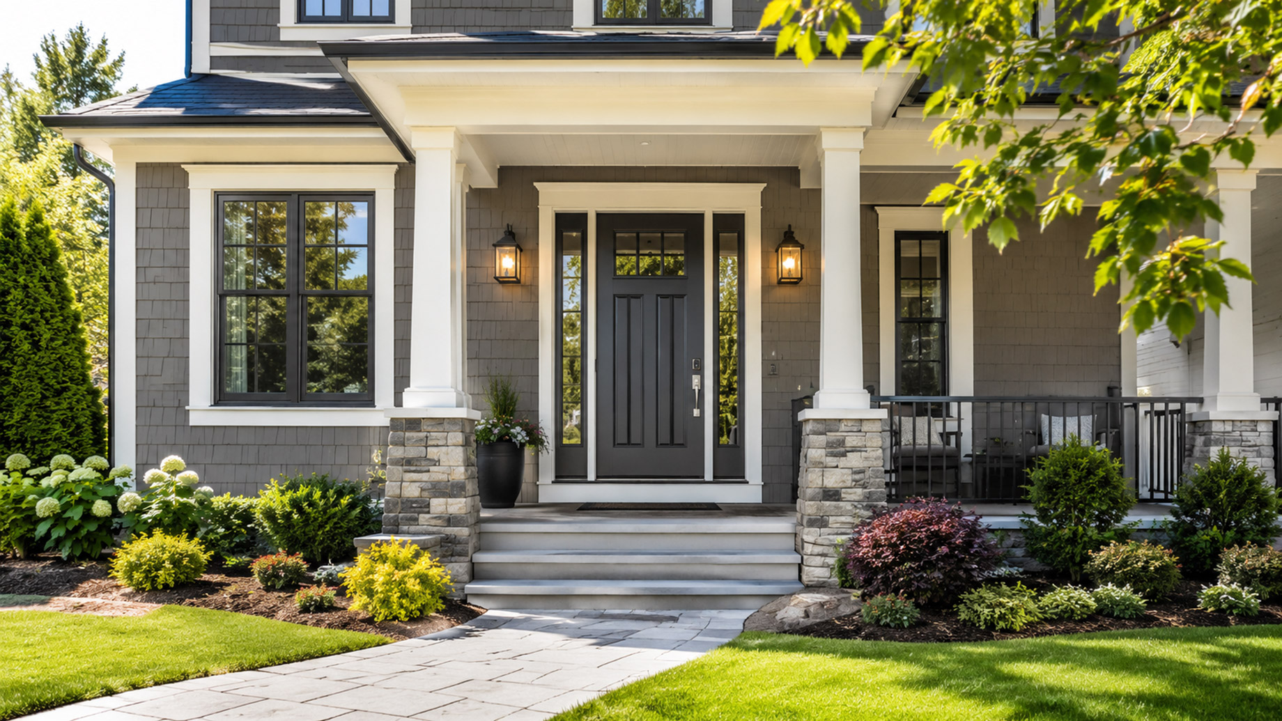Modern home exterior with a dark steel front door, stone accents, porch columns, landscaped entryway, and clean walkway.