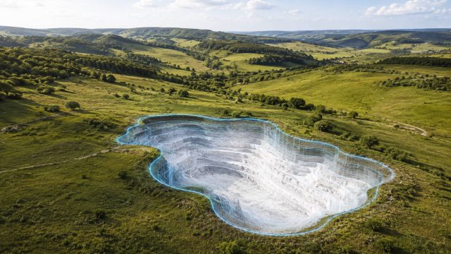 Rolling green countryside in Western Ukraine with an augmented-reality cutaway showing a proposed gypsum excavation beneath the land.