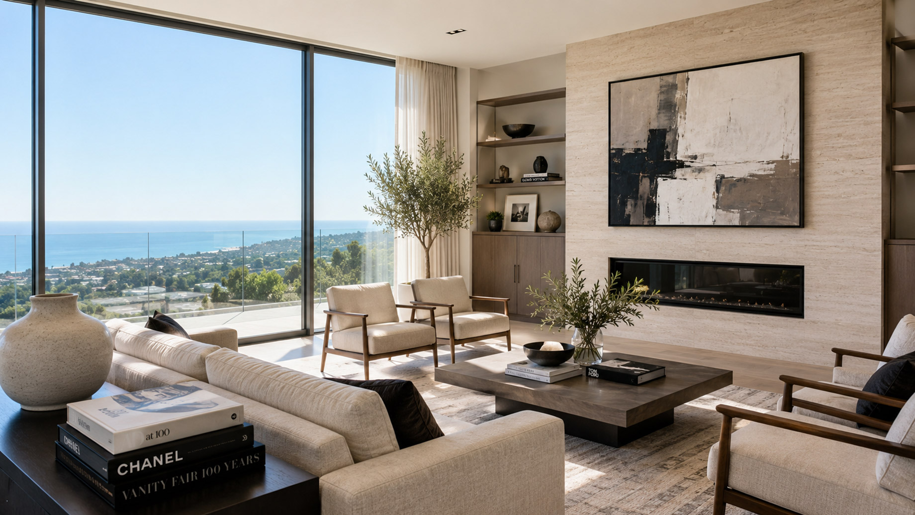 Bright modern luxury living room with cream seating, stone fireplace wall, curated decor, large windows, and a coastal view.