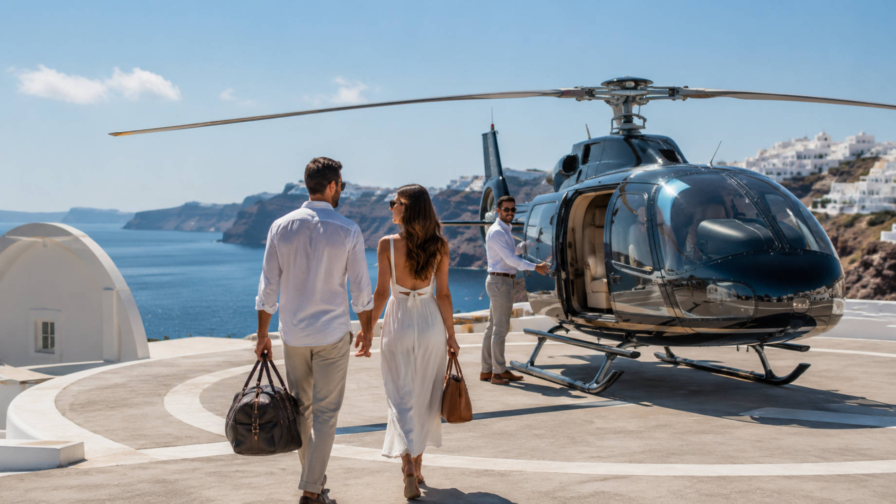 Luxury travellers approaching a private helicopter on a coastal helipad overlooking the Aegean Sea in Santorini.