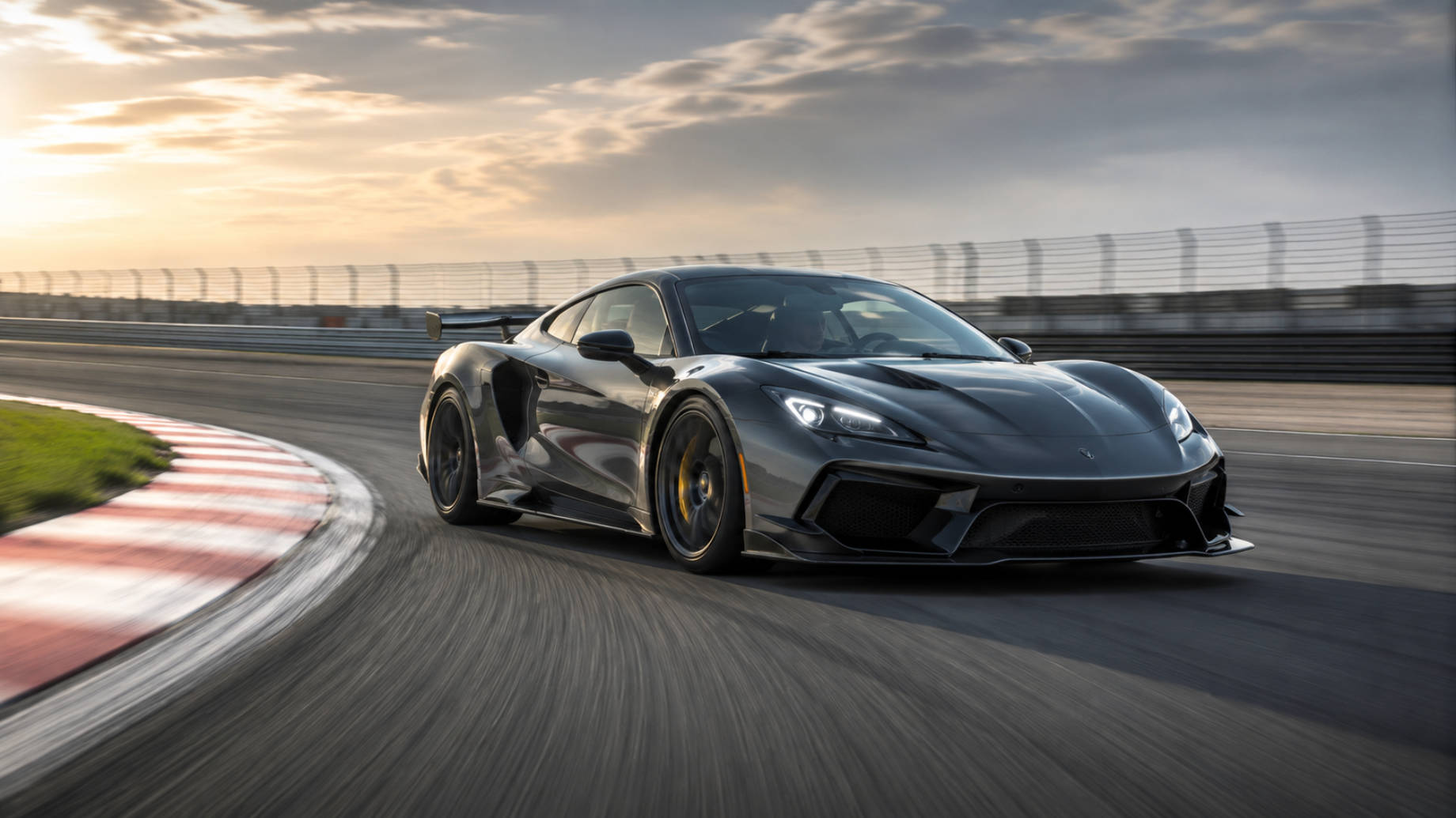 Dark performance car accelerating through a racetrack corner at golden hour with motion blur, track curbing, and a dramatic sky.