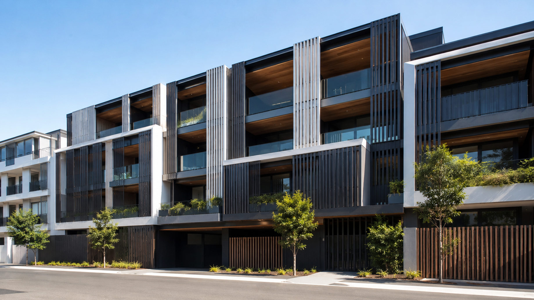 Contemporary Australian apartment building with vertical aluminium louvre panels screening balconies, windows, entrances, and lower-level service areas.