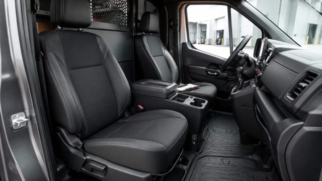 Commercial van cabin with durable upholstered seats, fitted rubber floor liners, practical storage, and a protective cargo partition.