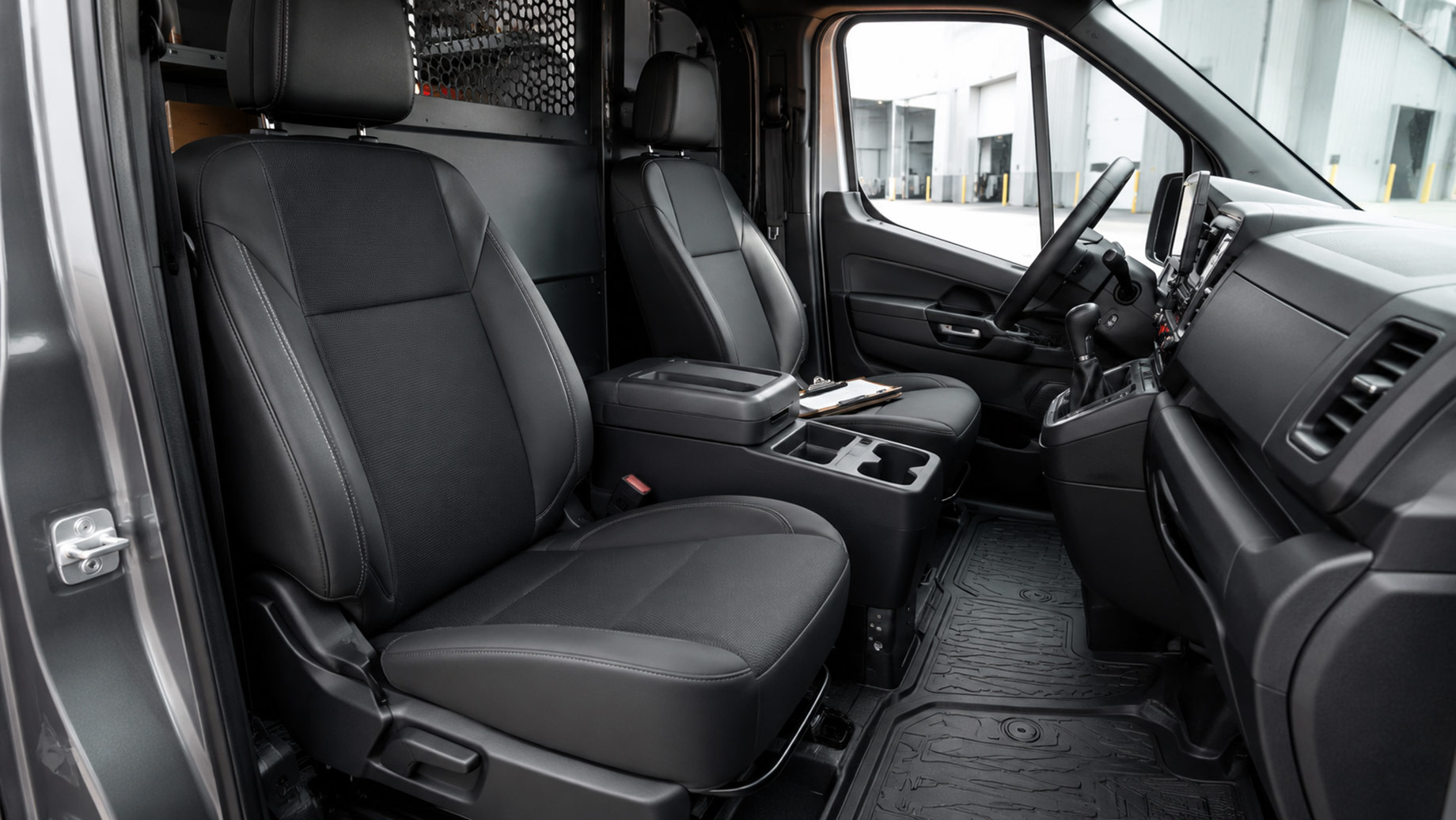 Commercial van cabin with durable upholstered seats, fitted rubber floor liners, practical storage, and a protective cargo partition.