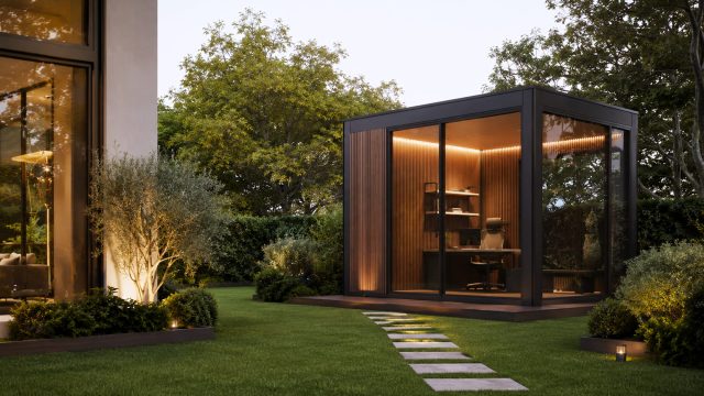 Modern glass office pod with timber walls and warm interior lighting positioned in the landscaped garden of a luxury home.