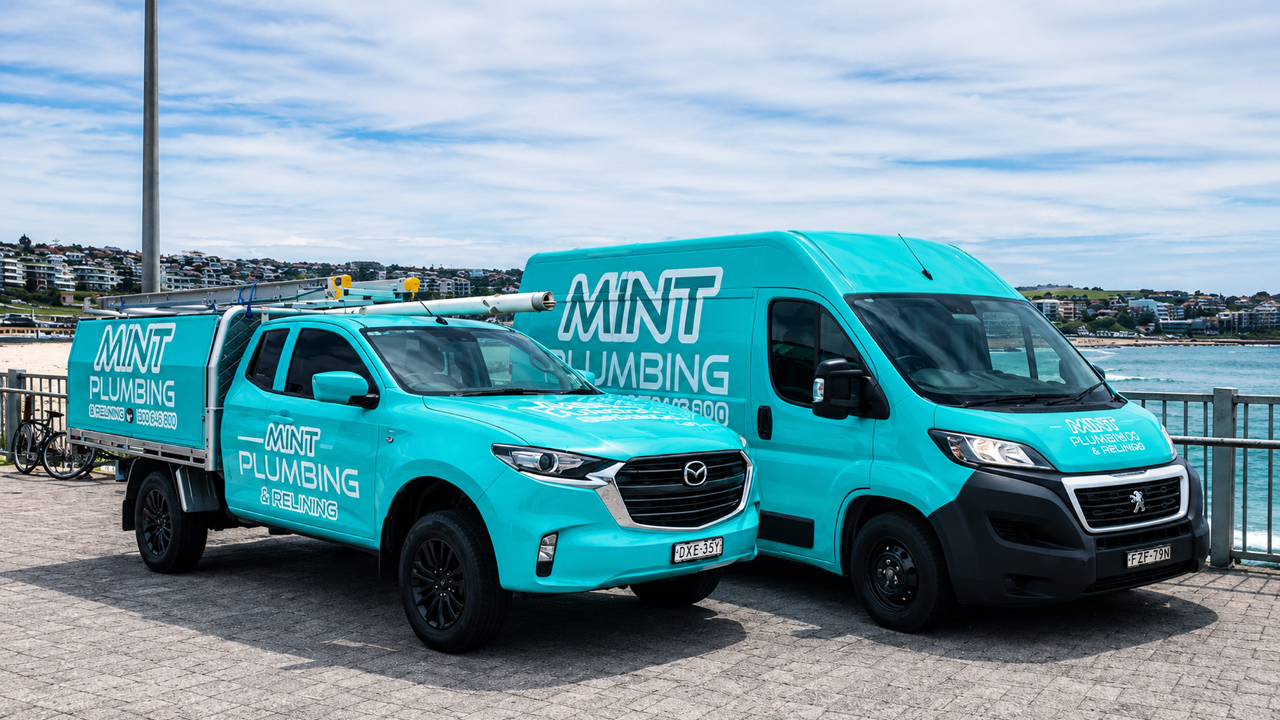 Mint Plumbing & Relining service truck and van parked beside the waterfront in Sydney, Australia.