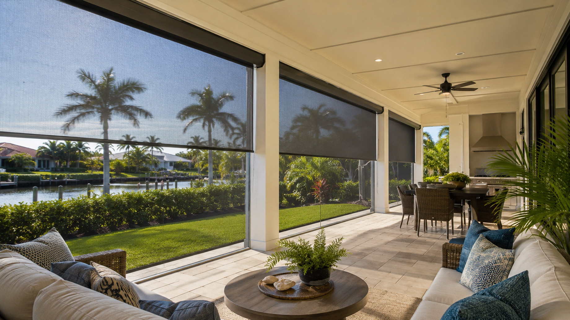 Covered Florida patio with lowered retractable screens, outdoor seating, dining area, palm trees, and waterfront views.