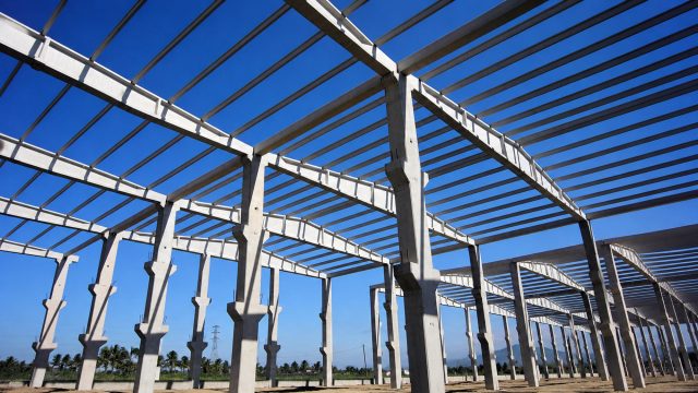 Large prefabricated structural frame under construction beneath a clear blue sky.