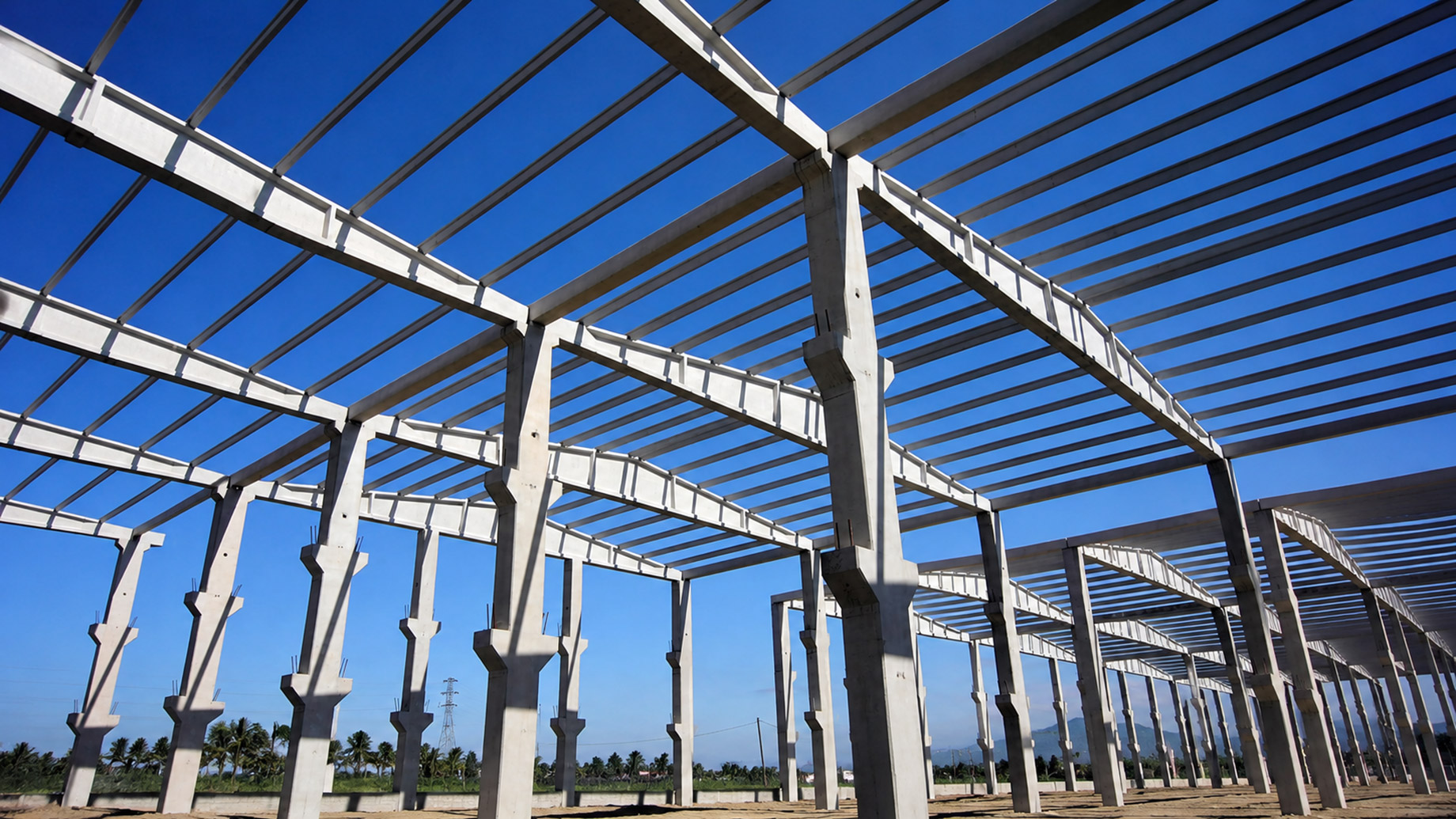 Large prefabricated structural frame under construction beneath a clear blue sky.