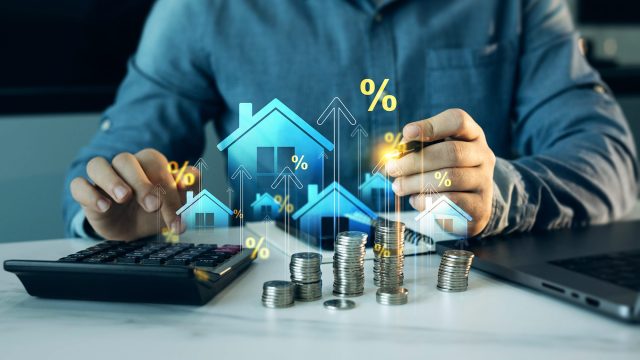 Investor reviews property finances beside stacked coins, a calculator, house symbols, rising arrows, and percentage graphics representing tax planning.