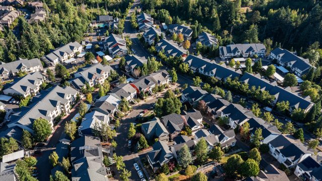 Aerial view of residential homes, apartment communities, tree-lined streets, and green spaces near Beaverton and Portland, Oregon.