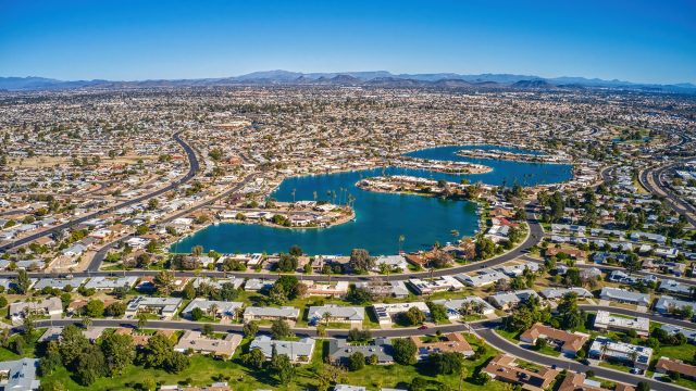 Aerial view of Sun City, Arizona, showing suburban neighborhoods, lakes, roads, and desert mountains across the Phoenix metropolitan area.