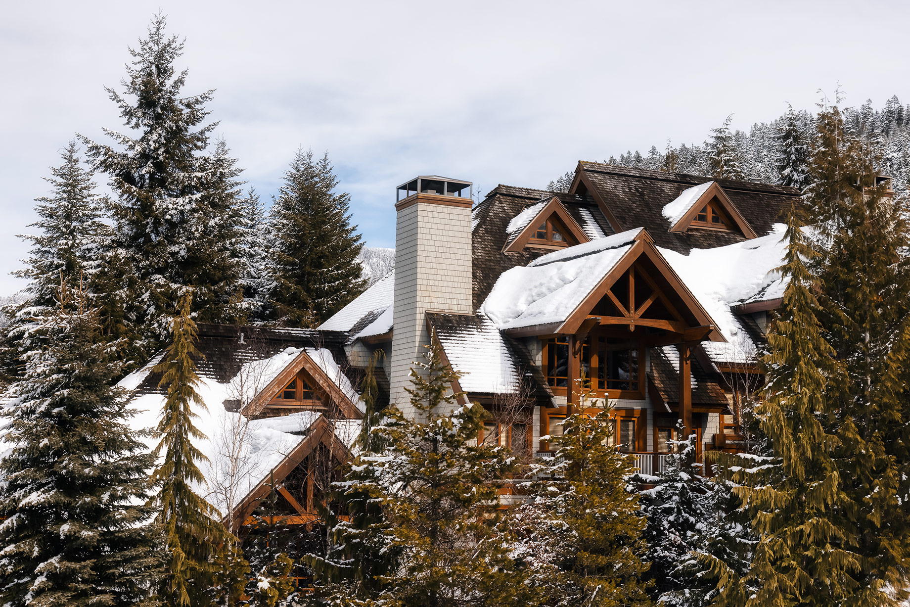 Snow-covered timber town homes surrounded by evergreen trees at Blackcomb in Whistler, British Columbia.