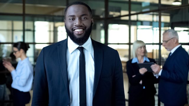 Baltimore attorney standing in a professional office with legal professionals working in the background.