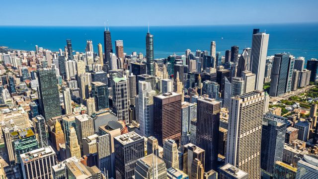 Aerial view of downtown Chicago skyscrapers beside Lake Michigan under a clear blue sky.