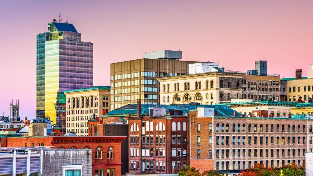 Downtown Worcester, Massachusetts skyline with historic brick buildings and modern high-rises beneath a colorful evening sky.