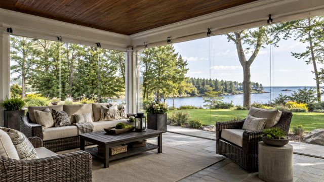 Elegant covered porch with clear vinyl enclosure panels, comfortable outdoor furniture, natural light, landscaped gardens, and uninterrupted waterfront views.