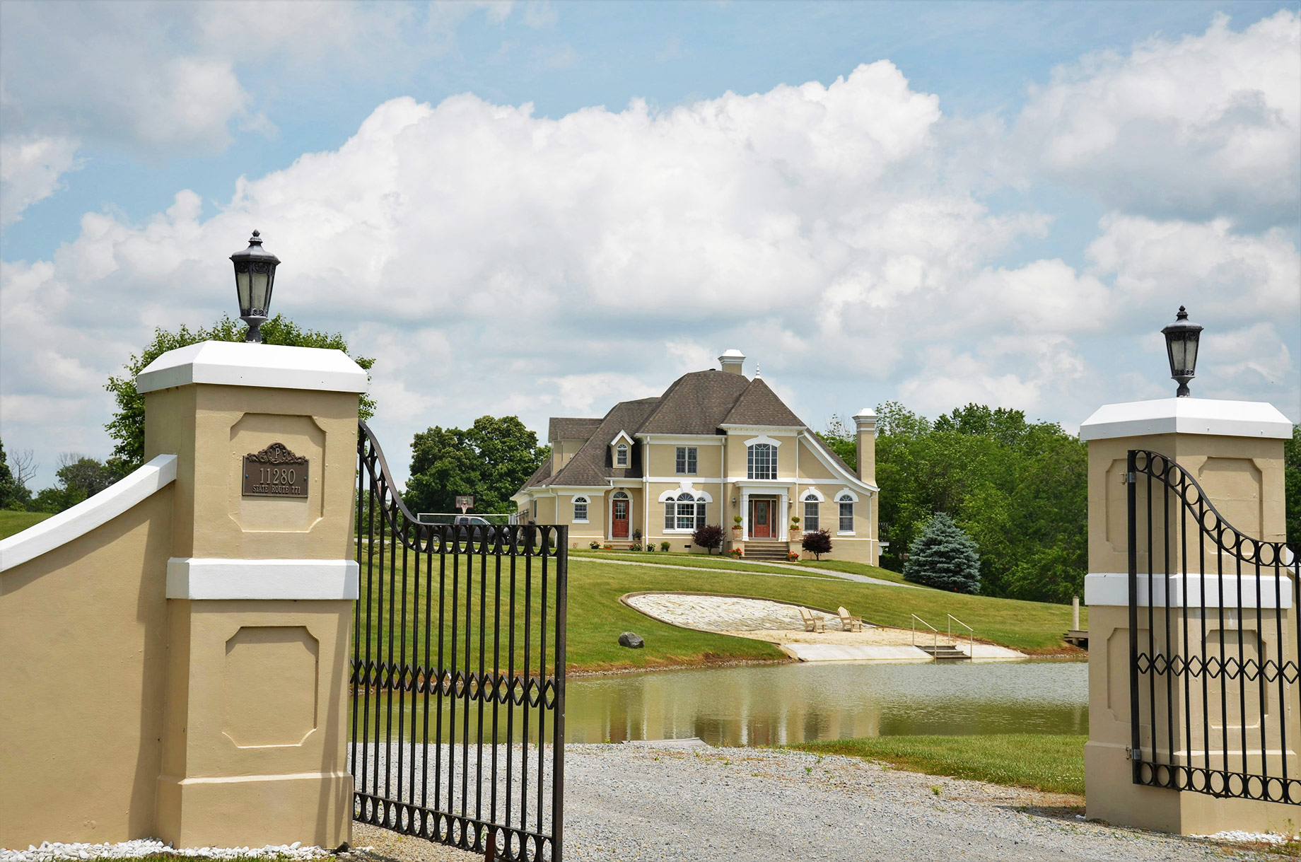 Wrought-iron security gates protecting the entrance to a large luxury home with secluded grounds.