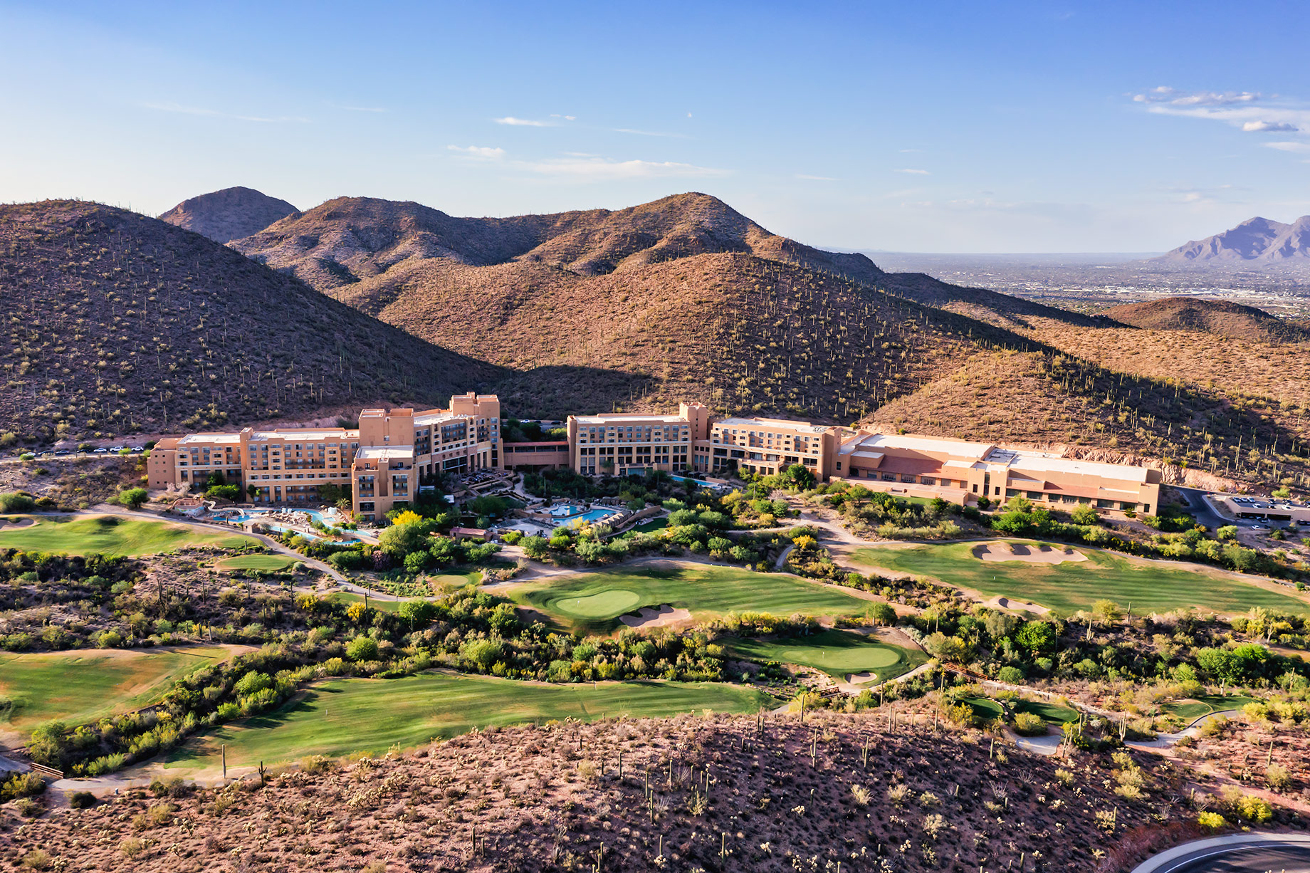 Aerial view of a luxury resort and golf course surrounded by the Sonoran Desert and rugged mountains in Tucson, Arizona.