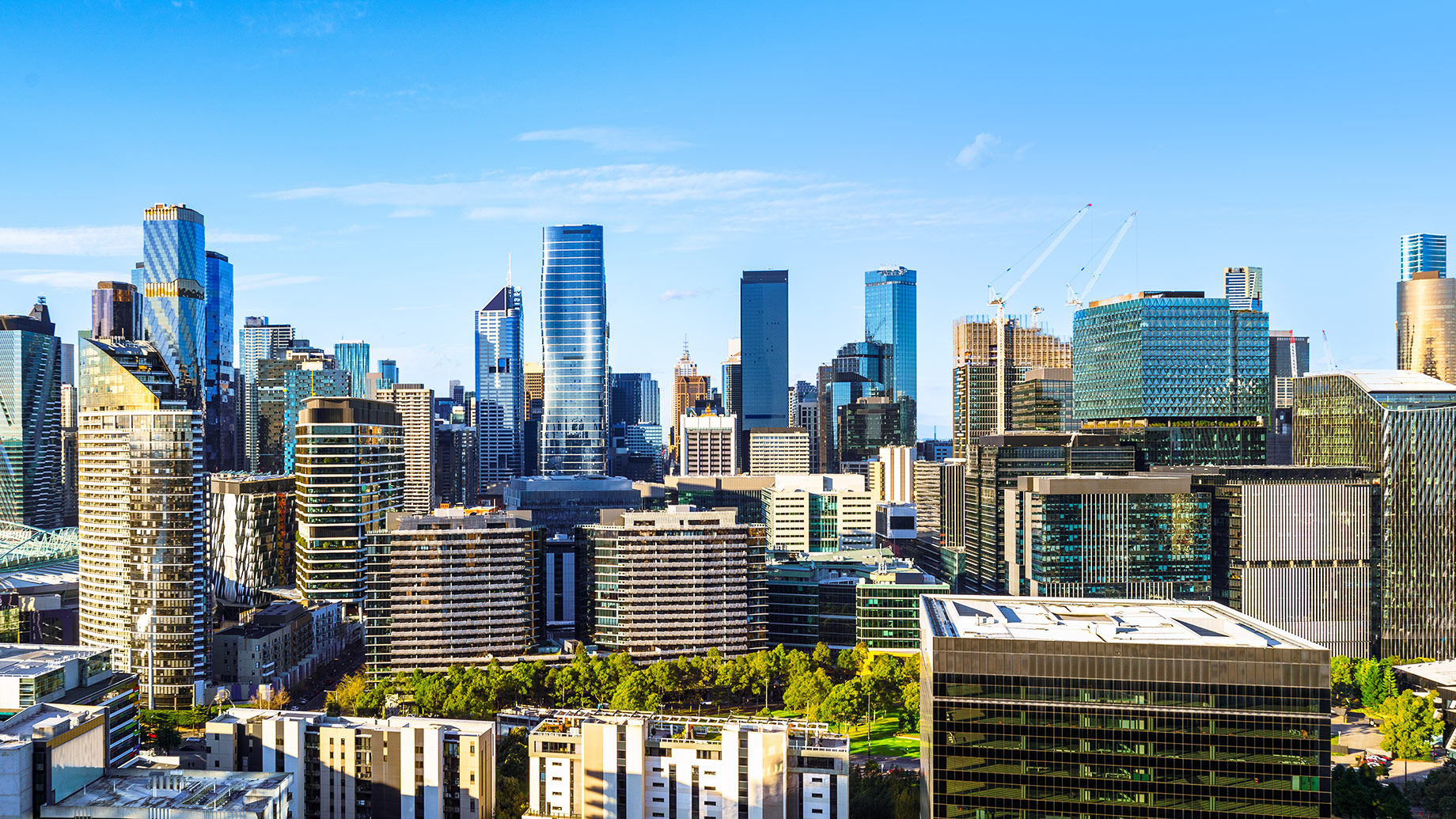 Melbourne CBD skyline featuring modern residential and commercial towers under a clear blue sky.