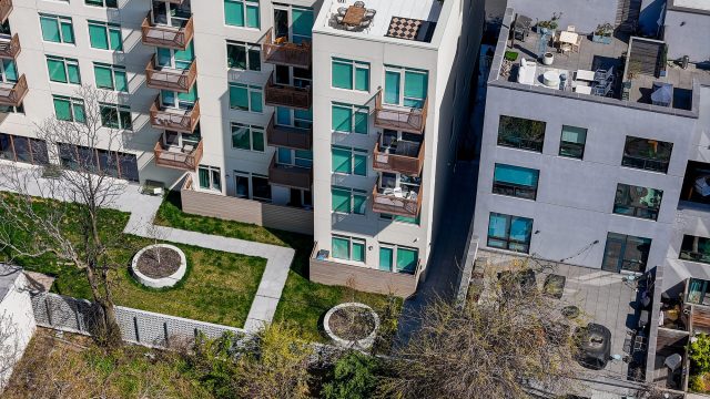 Aerial view of multifamily apartment buildings with balconies, rooftop terraces, and landscaped shared spaces in Brooklyn, New York City.