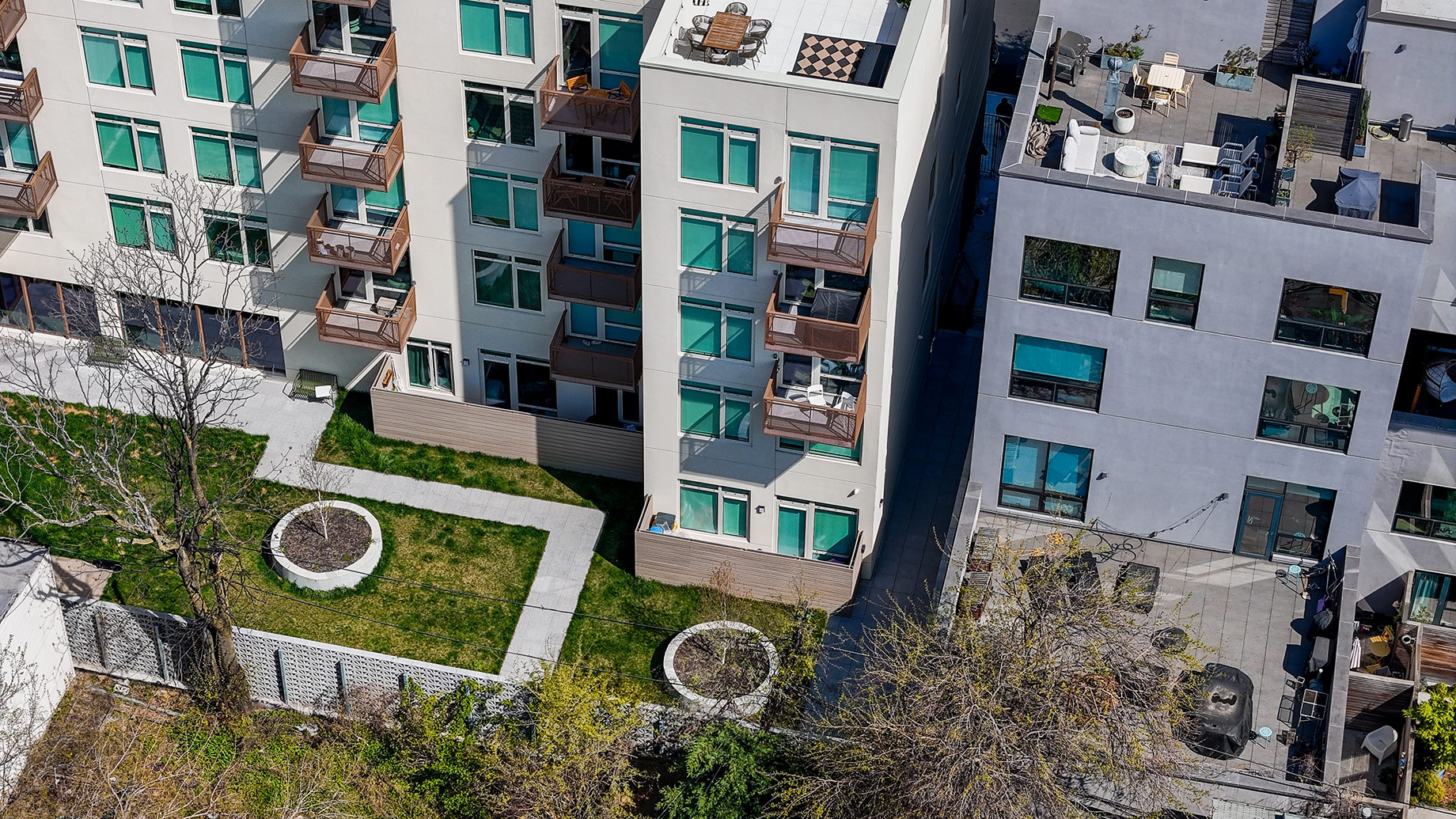 Aerial view of multifamily apartment buildings with balconies, rooftop terraces, and landscaped shared spaces in Brooklyn, New York City.