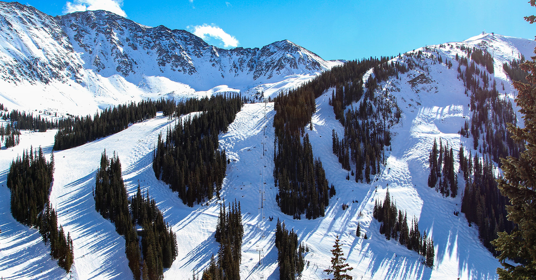 Steep snowy ski slopes and evergreen-covered mountain ridges near Keystone, Colorado.