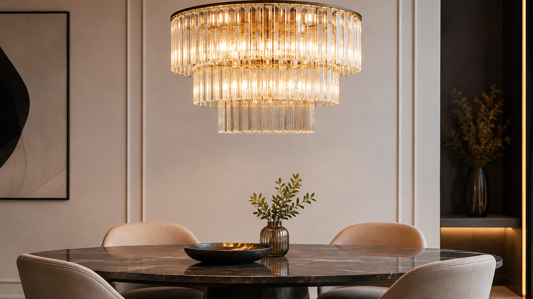 Tiered glass-and-brass chandelier illuminating a dark marble dining table with neutral upholstered chairs in a contemporary interior.