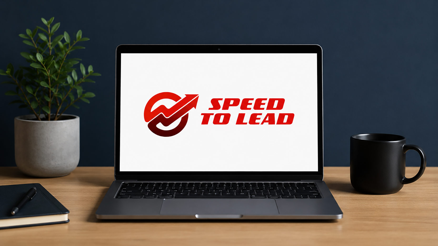 Laptop displaying the iSpeedToLead logo on a clean office desk with a plant, notebook, and coffee mug.