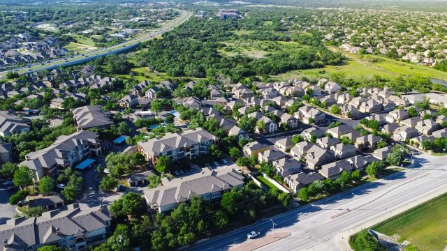 Aerial view of apartment communities, single-family homes, roads, and green space in Cedar Park near Austin, Texas.