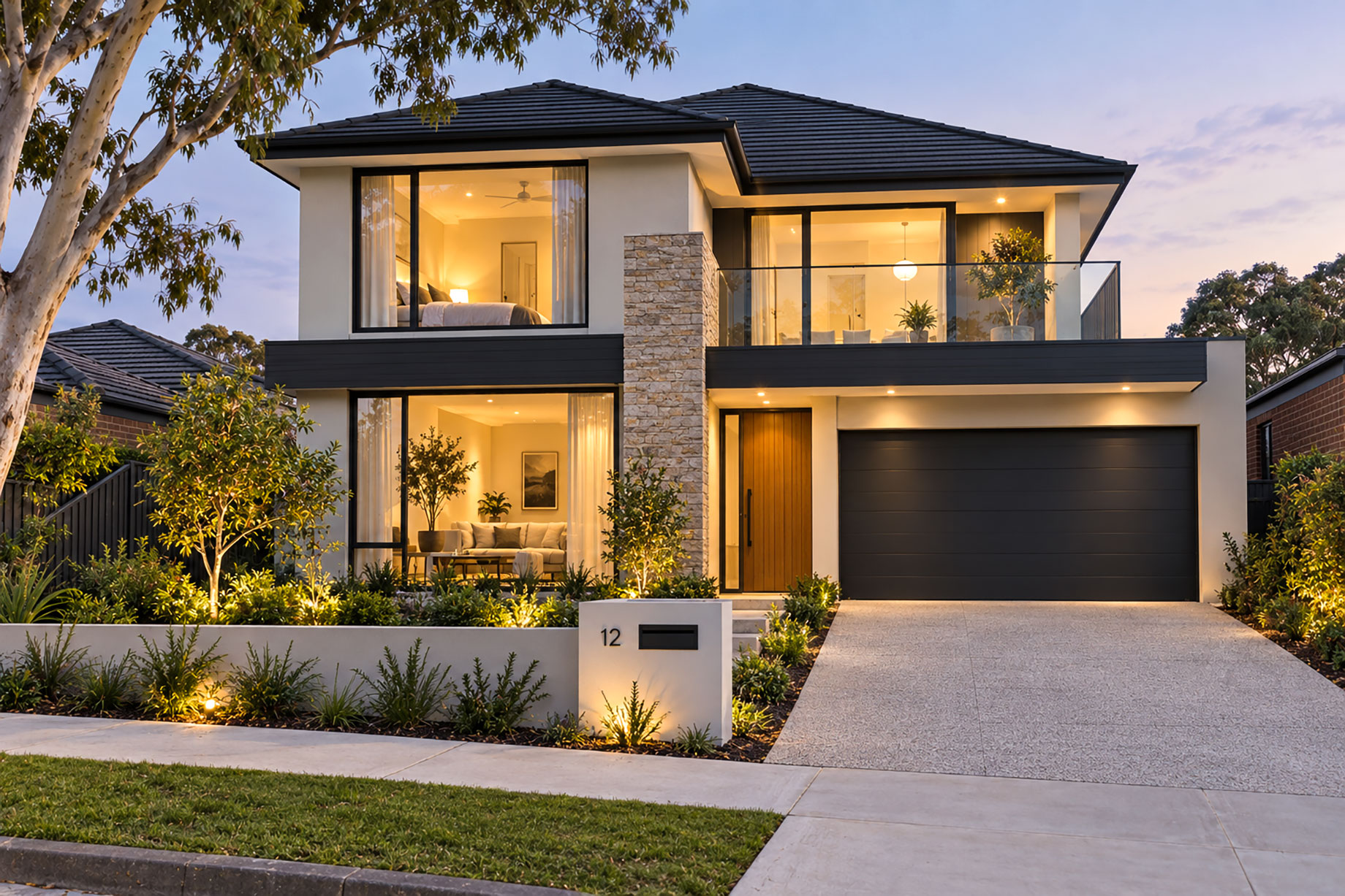 Two-storey home with a glass balcony, stone feature wall, timber entrance, dark double garage, and landscaped front garden at dusk.