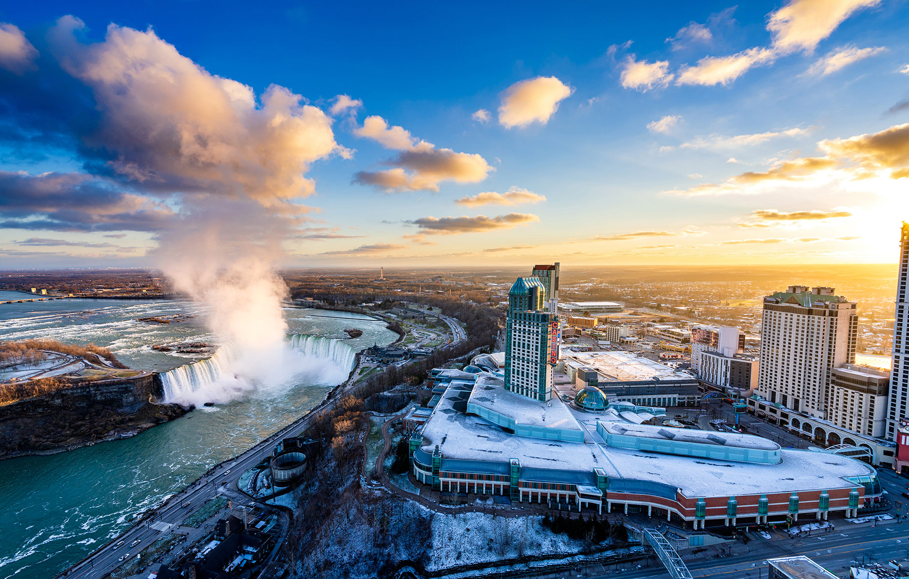 Aerial view of Horseshoe Falls and Fallsview Casino Resort beneath a vivid winter sunset in Niagara Falls, Ontario.
