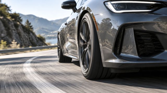 Sports car carving through a mountain bend, highlighting the grip and control that high-performance tires provide.