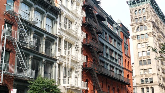 Historic cast-iron and brick buildings with exterior fire escapes along Broome Street in Manhattan’s SoHo neighborhood.