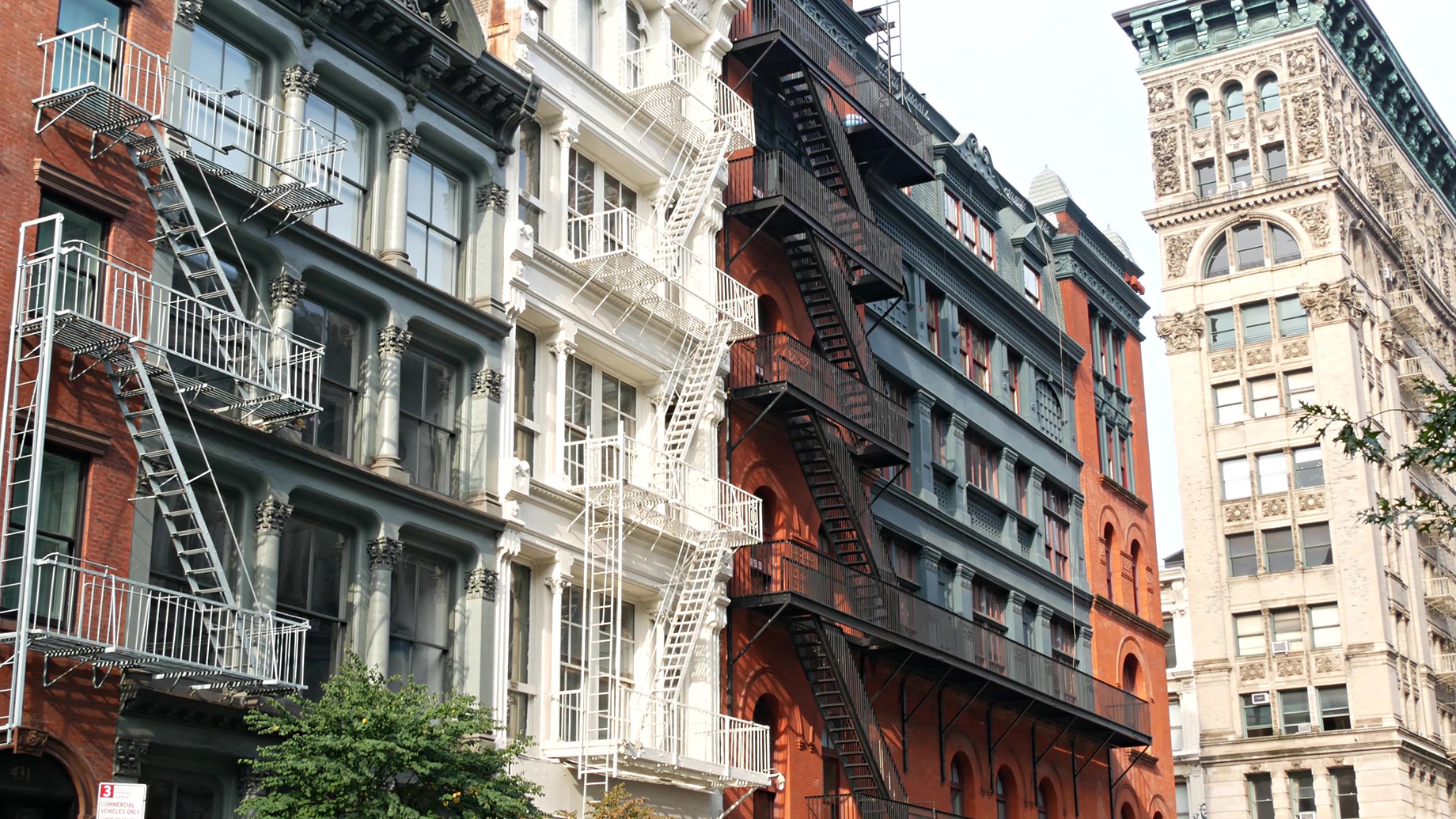 Historic cast-iron and brick buildings with exterior fire escapes along Broome Street in Manhattan’s SoHo neighborhood.
