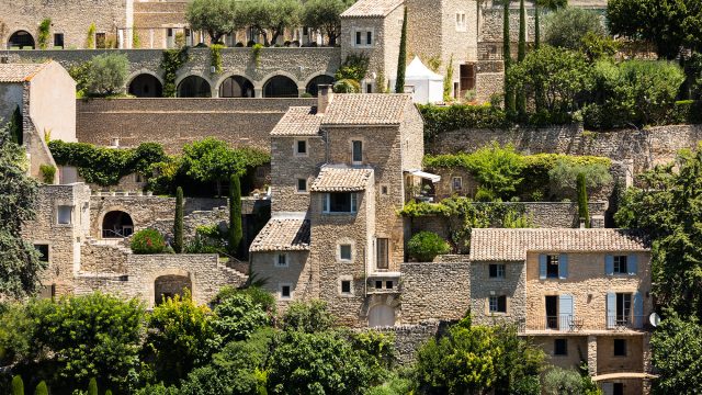 Sunlit stone houses and terracotta roofs in the medieval hilltop town of Gordes, Provence, France.