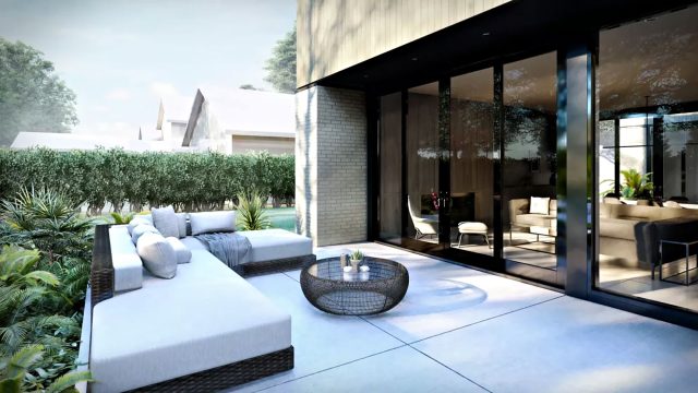 Black-framed glass doors beside a paved terrace with a white outdoor sectional, round woven coffee table, and lush garden planting.