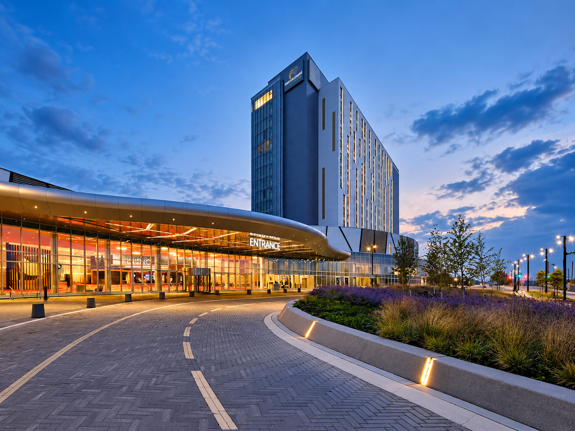 Illuminated entrance and hotel tower at Pickering Casino Resort beneath a blue evening sky.