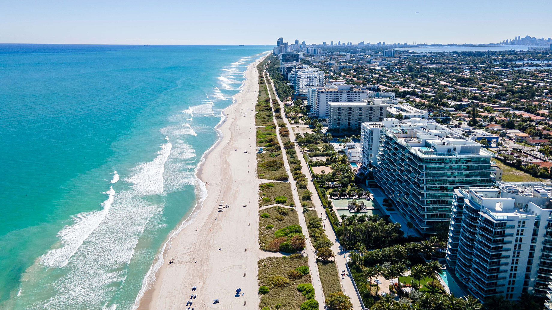 Aerial view of Surfside Beach, Florida, with turquoise water, a sandy shoreline, and oceanfront condominium buildings.