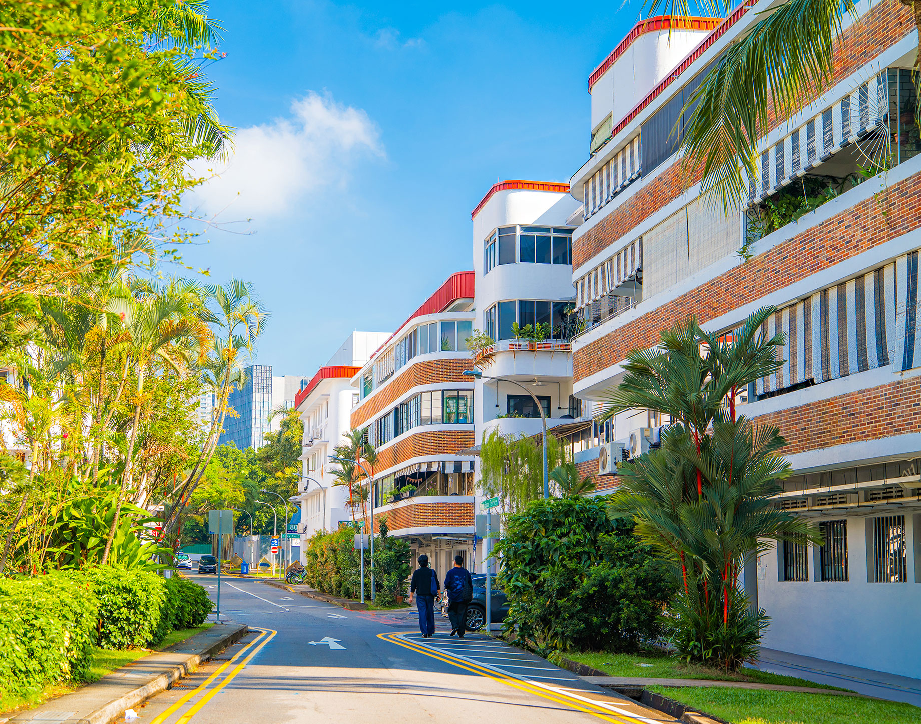 White heritage buildings with red-brick bands and striped awnings line a leafy street in Singapore’s Tiong Bahru neighbourhood.