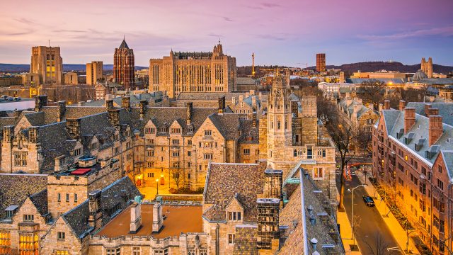 Elevated view across Yale University’s historic Gothic architecture and the New Haven skyline under a soft evening sky.