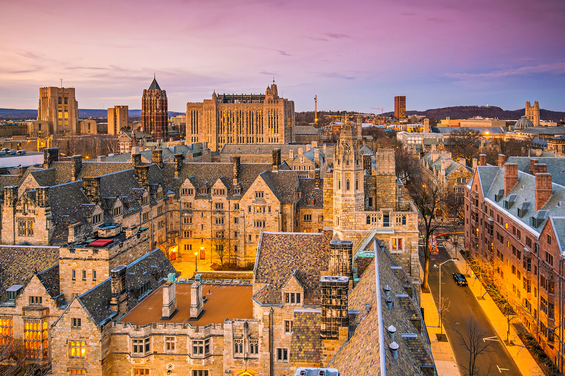 Elevated view across Yale University’s historic Gothic architecture and the New Haven skyline under a soft evening sky.