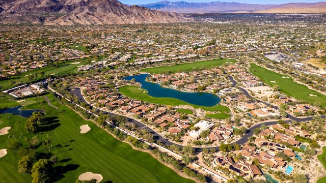 Aerial landscape of golf courses in Palm Desert, California, surrounded by the desert terrain and mountains of the Coachella Valley.