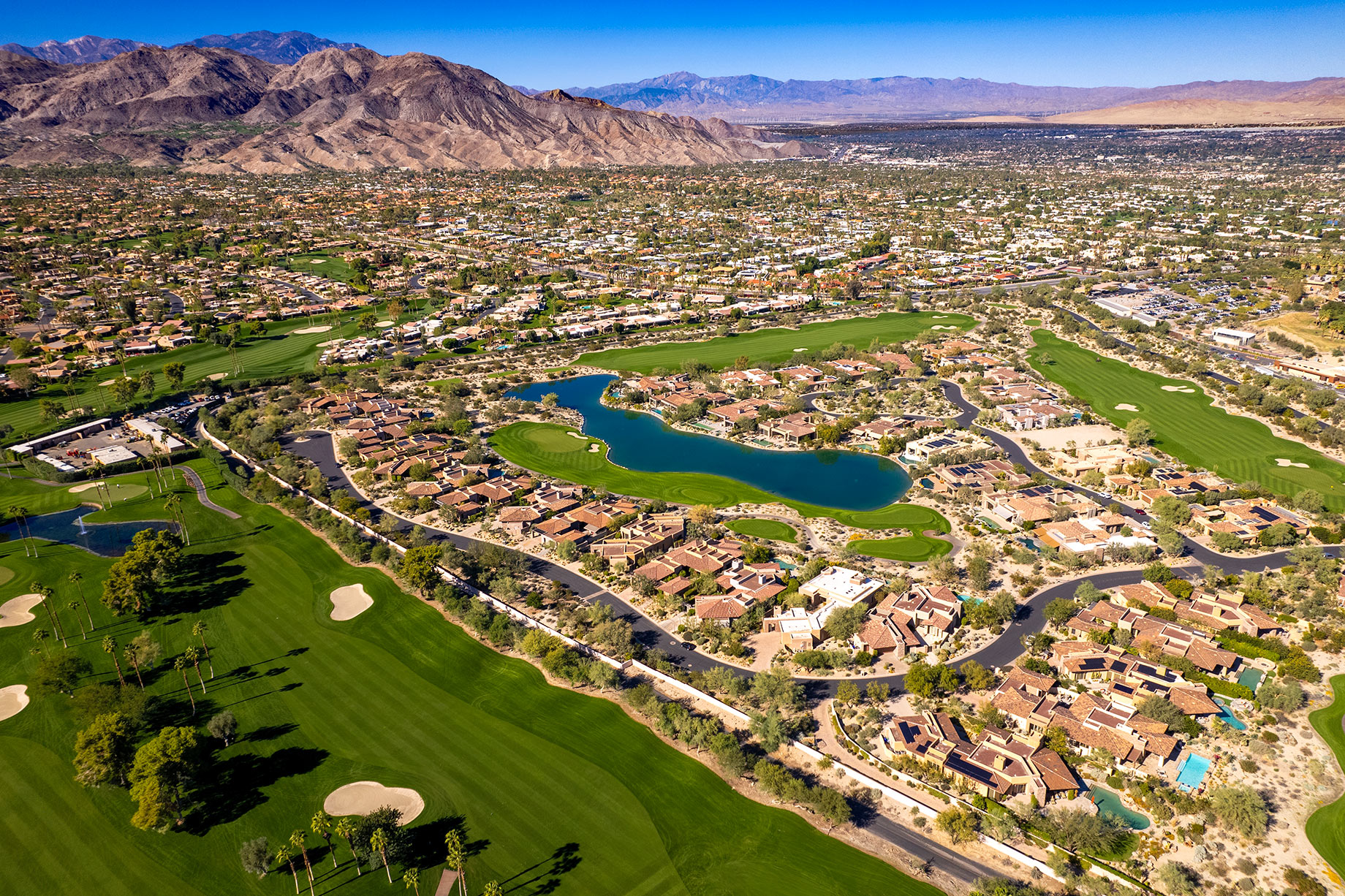 Aerial landscape of golf courses in Palm Desert, California, surrounded by the desert terrain and mountains of the Coachella Valley.