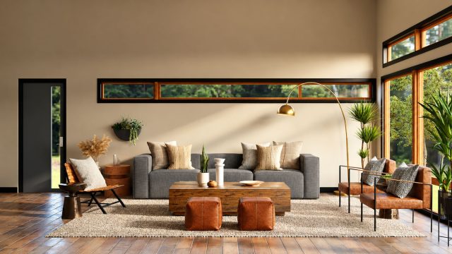 Living room with a gray sofa, wooden coffee table, leather ottomans and a brass arc lamp beside tall windows.