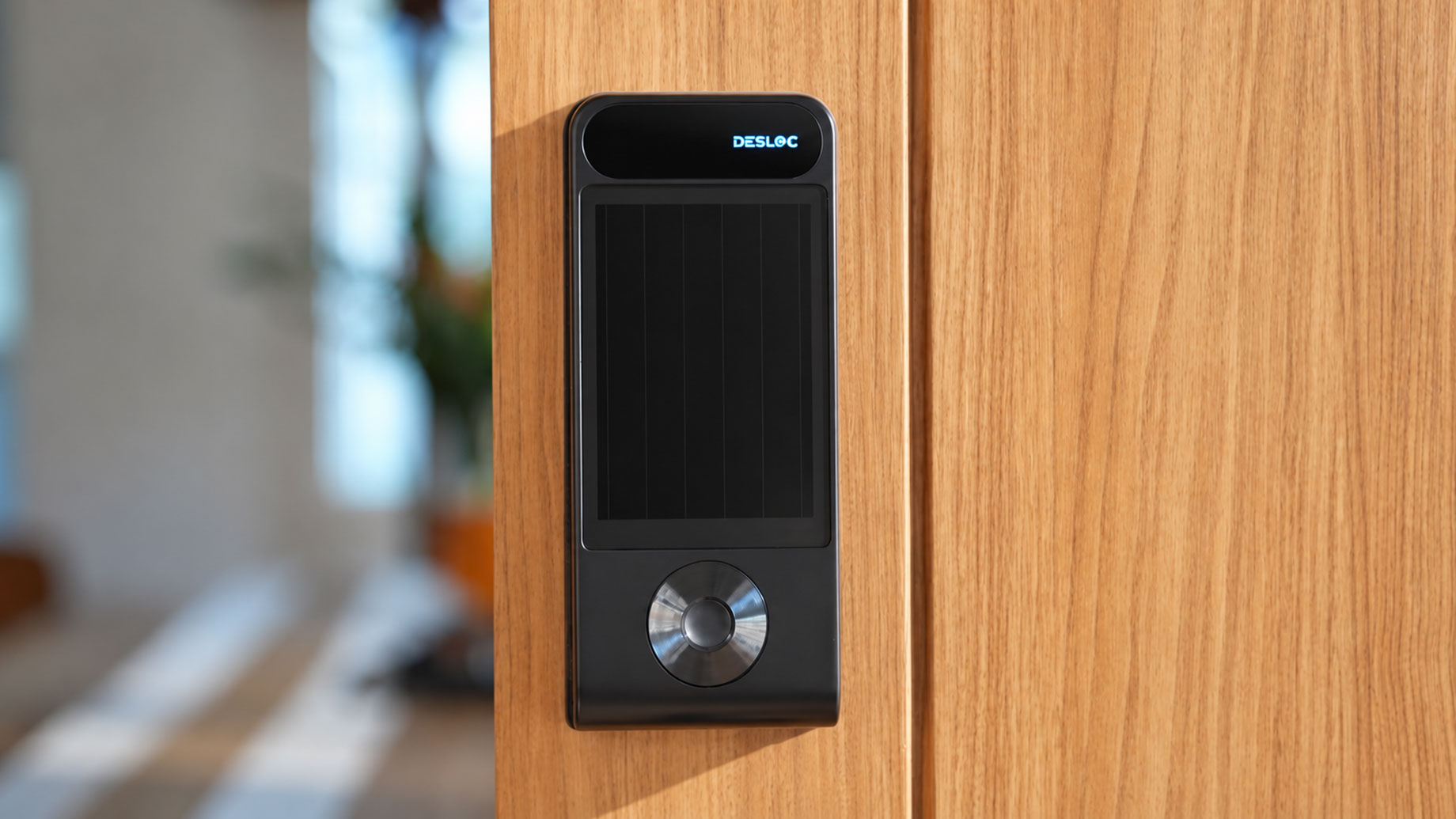 Close-up of a DESLOC V150 Plus smart lock mounted on a natural wood door in a contemporary home.