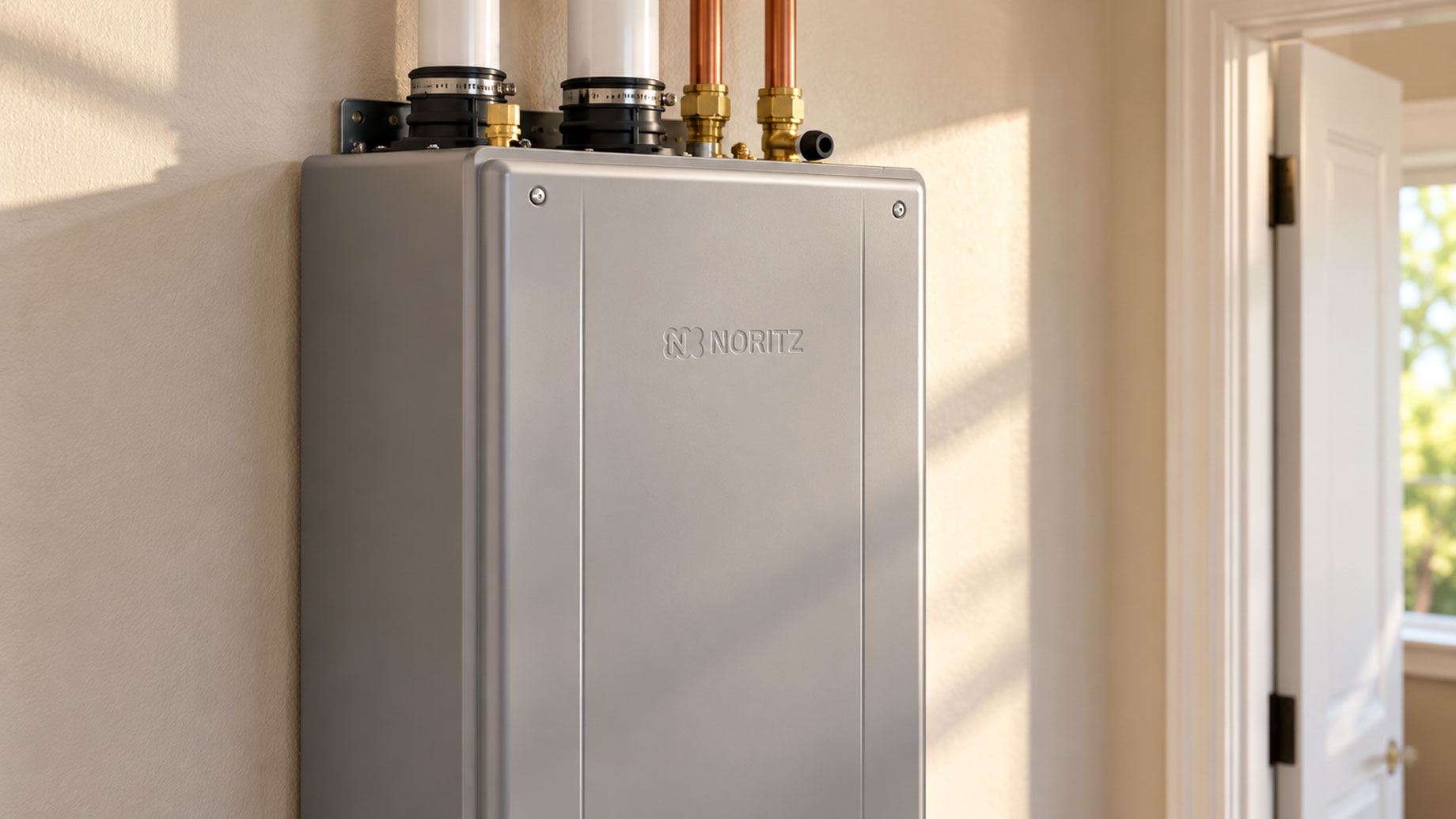 Grey Noritz tankless water heater mounted on a cream utility-room wall beside an open doorway.