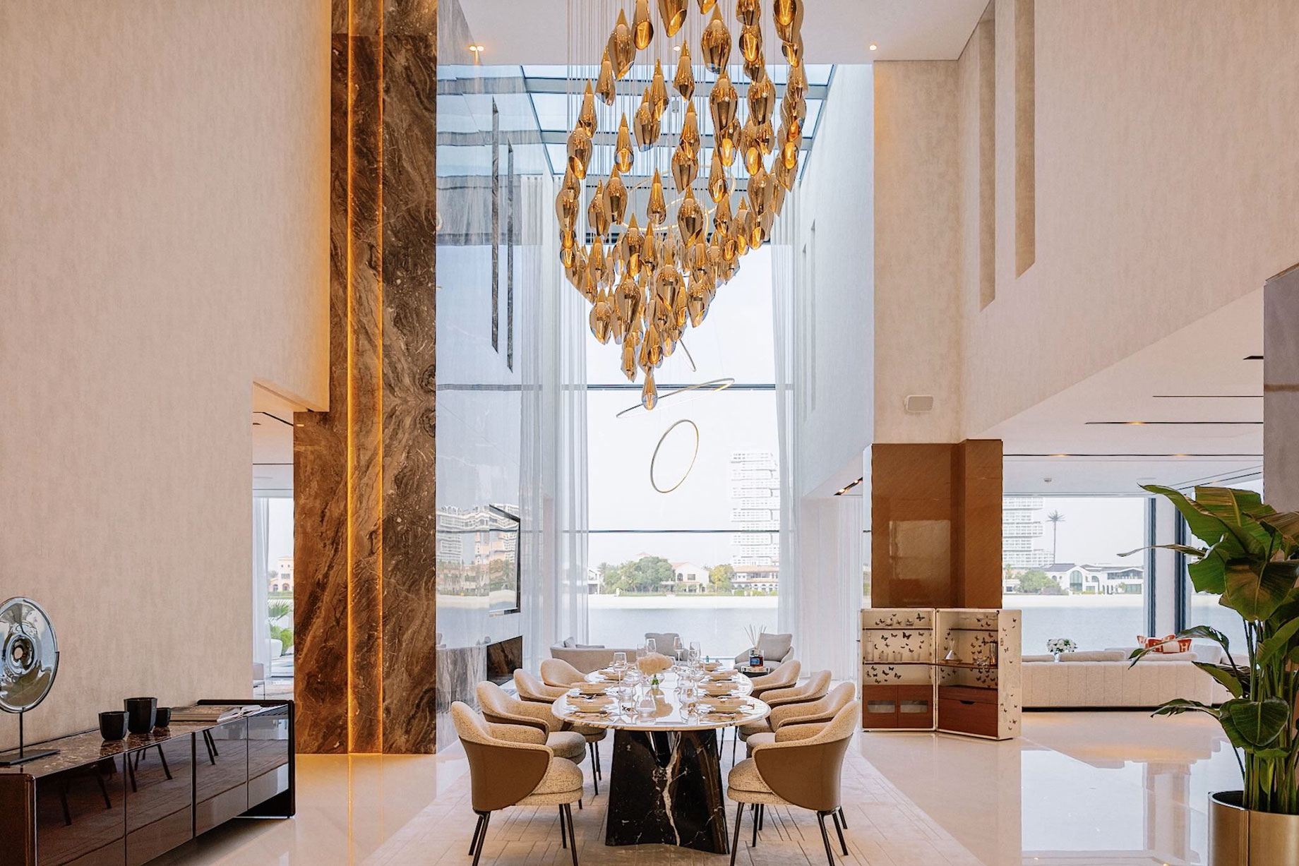 Double height dining room with a sculptural chandelier in a Palm Jumeirah villa.