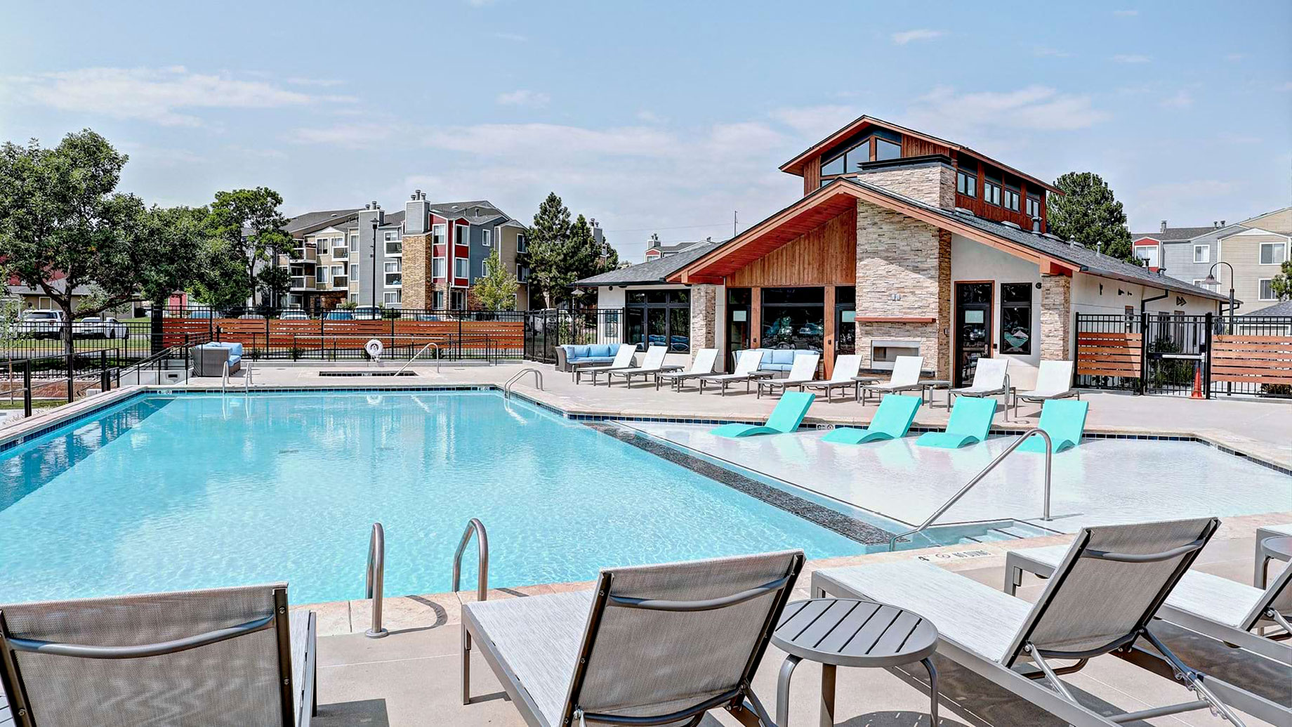 Swimming pool with turquoise in-water loungers, poolside seating and a stone-and-wood clubhouse at Parc at Cherry Creek.